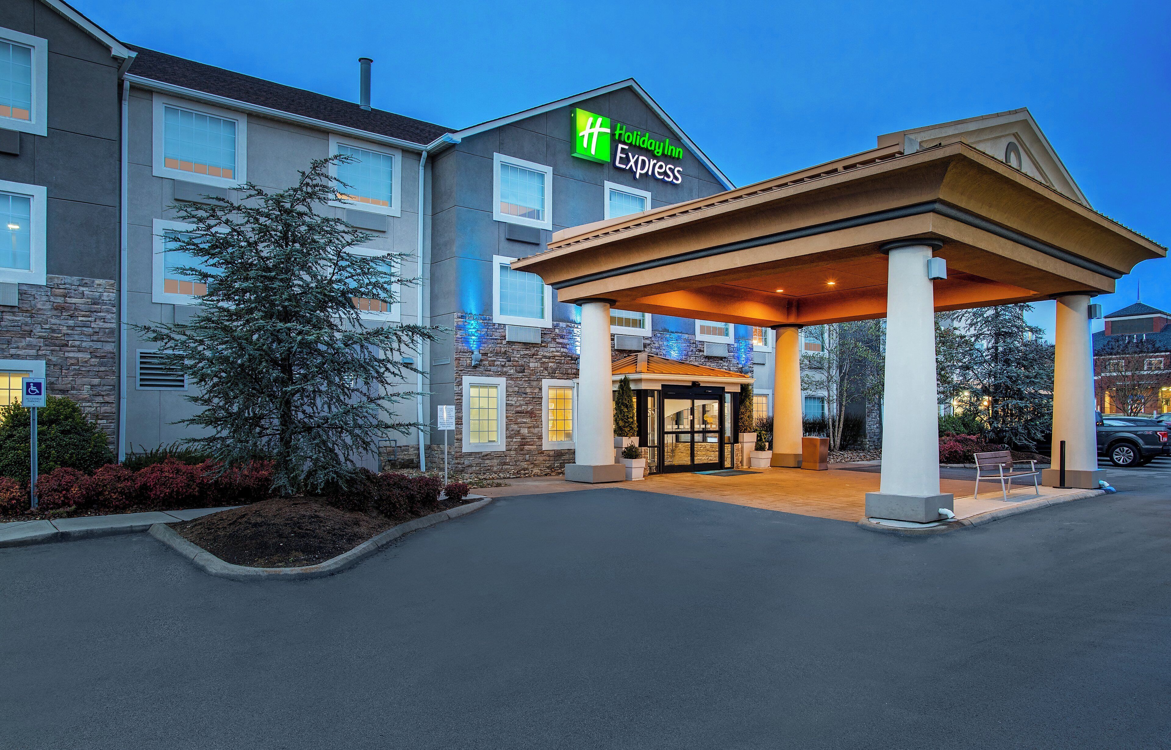 A Holiday Inn Express hotel with a covered entrance, stone facade, and a parking lot.