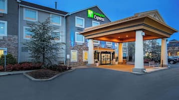 A Holiday Inn Express hotel with a covered entrance, stone facade, and a parking lot.