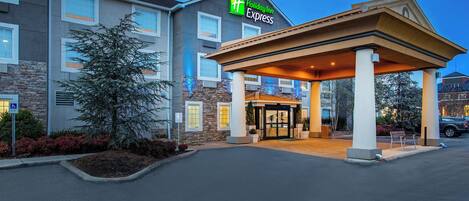 Een Holiday Inn Express hotel met een overdekte ingang, een gevel van natuursteen en een parkeerplaats.