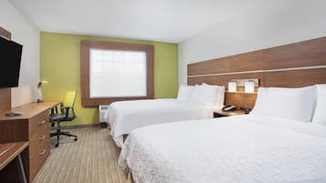 A hotel room with two beds, a desk, a chair, a television, and a window.