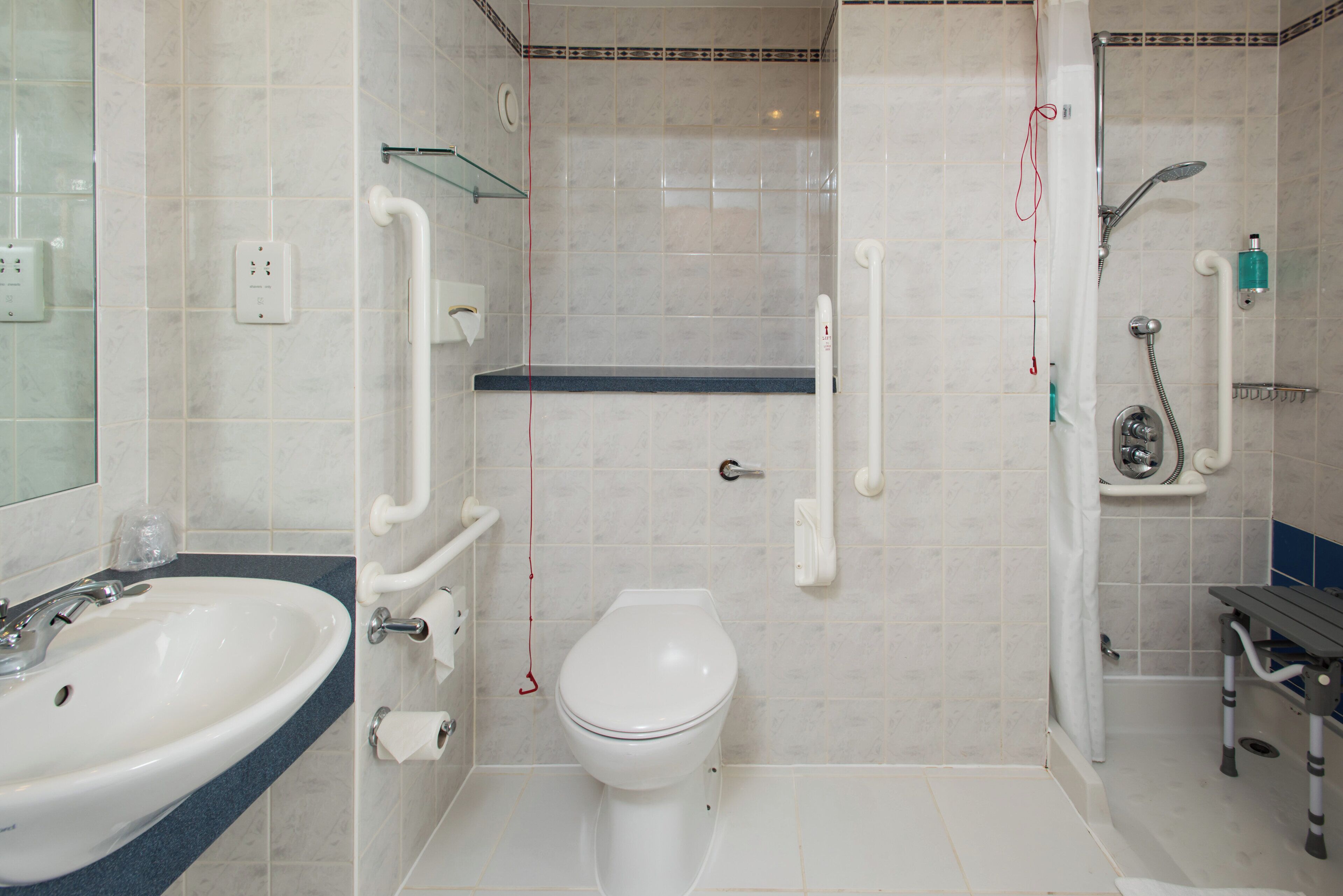 Et badeværelse med vask, toilet og bruseområde.