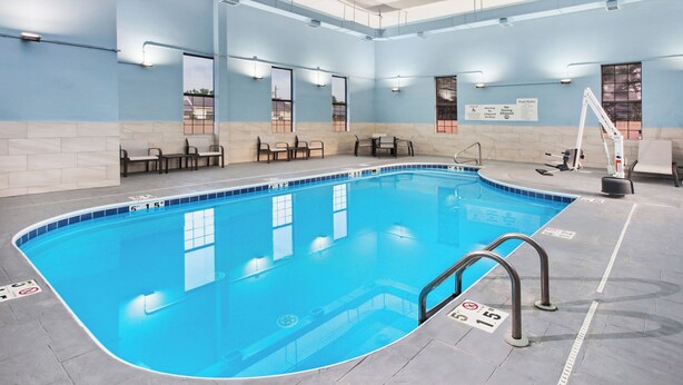 An indoor swimming pool with clear water, tiled edges, and a lifeguard stand. - Holiday Inn Express Cleveland Airport - Brookpark by IHG (Brook Park)