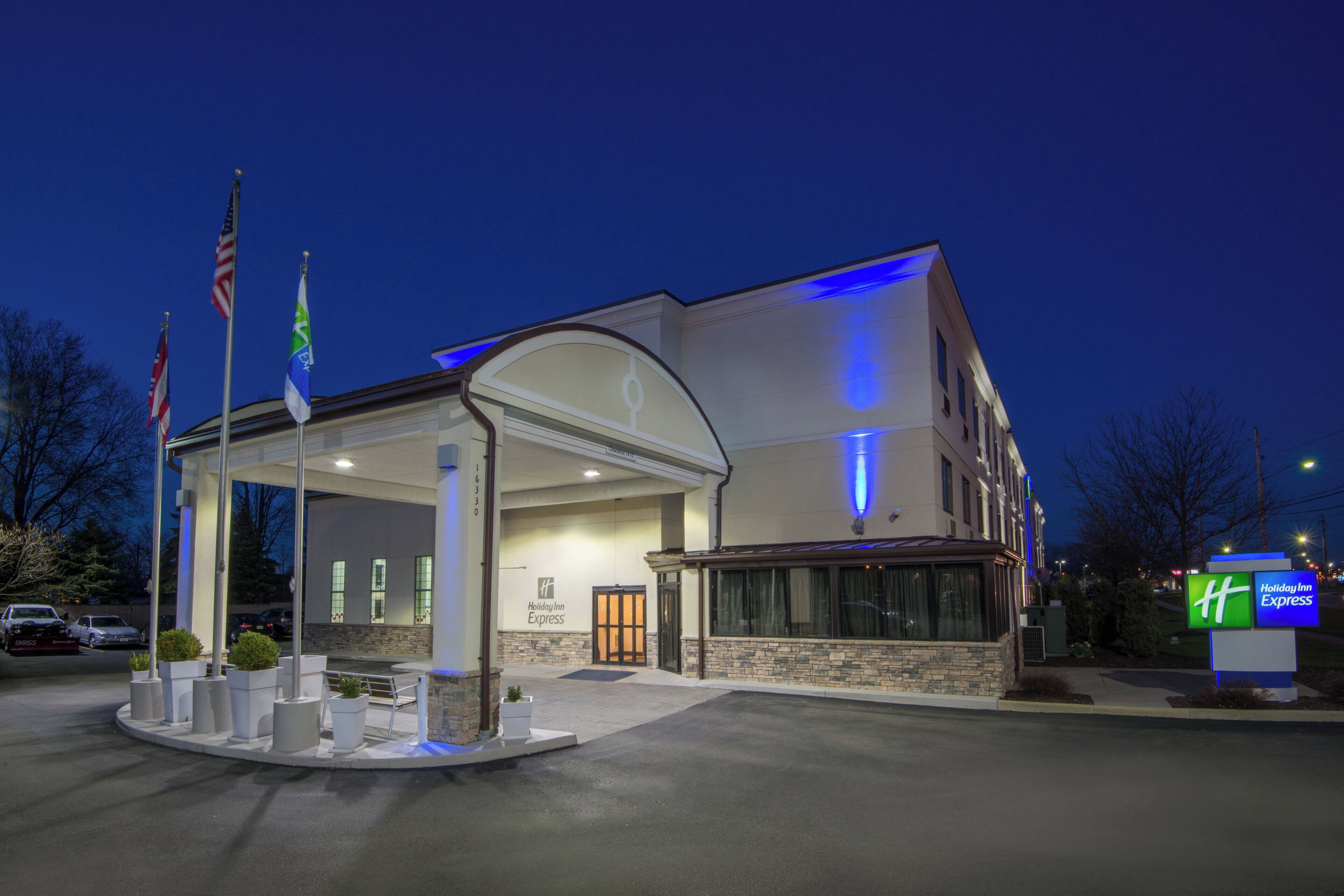 A Holiday Inn Express hotel with a covered entrance, American flags, and a stone facade.