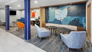 A modern lobby with seating areas, a map mural, and a flat-screen TV on the wall. - Holiday Inn Express Cleveland Airport - Brookpark by IHG (Brook Park)