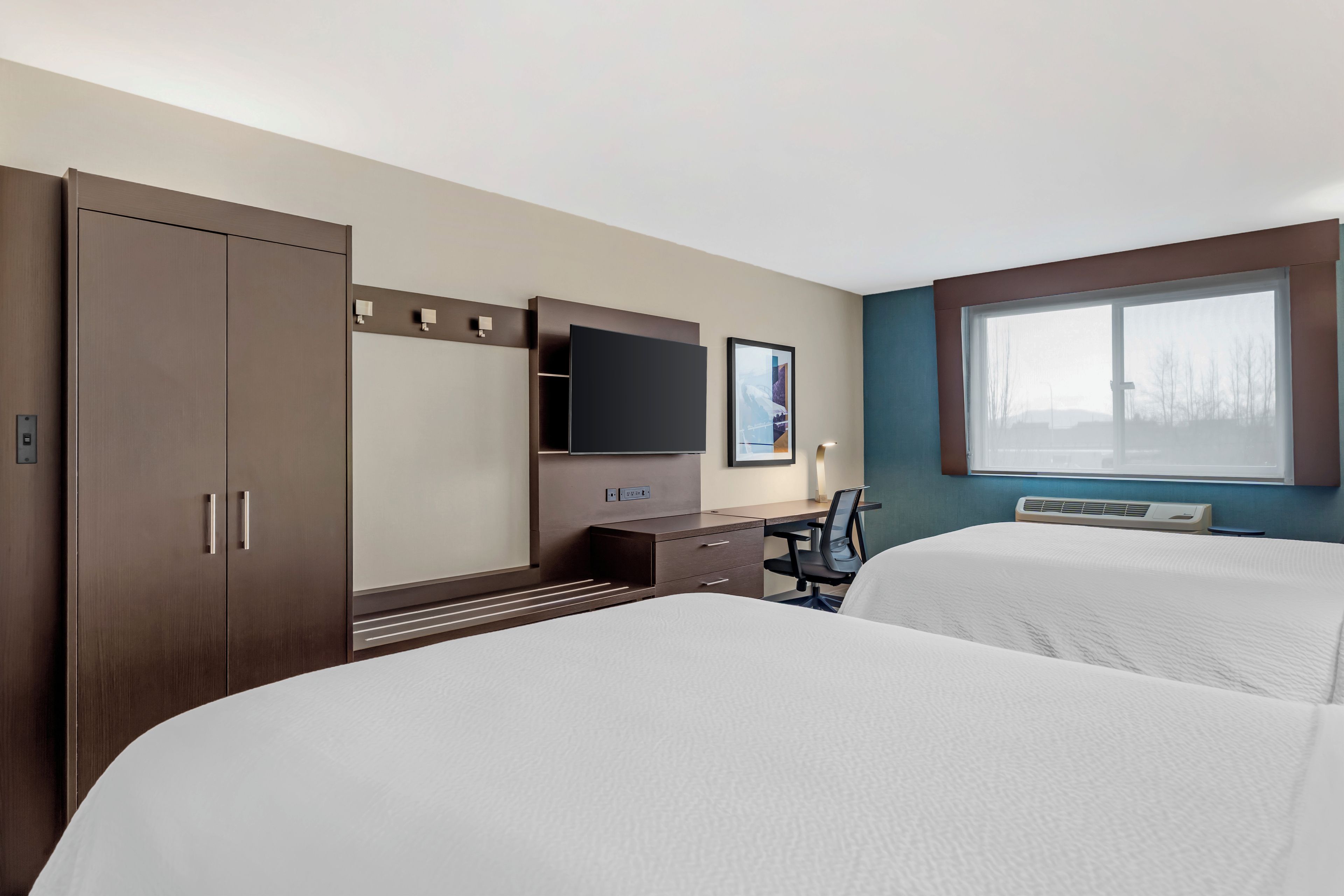 Ein Hotelzimmer mit Bett, Schreibtisch, Fernseher und Fenster.