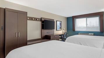 Ein Hotelzimmer mit Bett, Schreibtisch, Fernseher und Fenster.