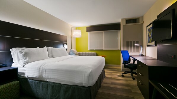 Una camera d'albergo con un letto, una scrivania, una sedia, una televisione e una finestra.