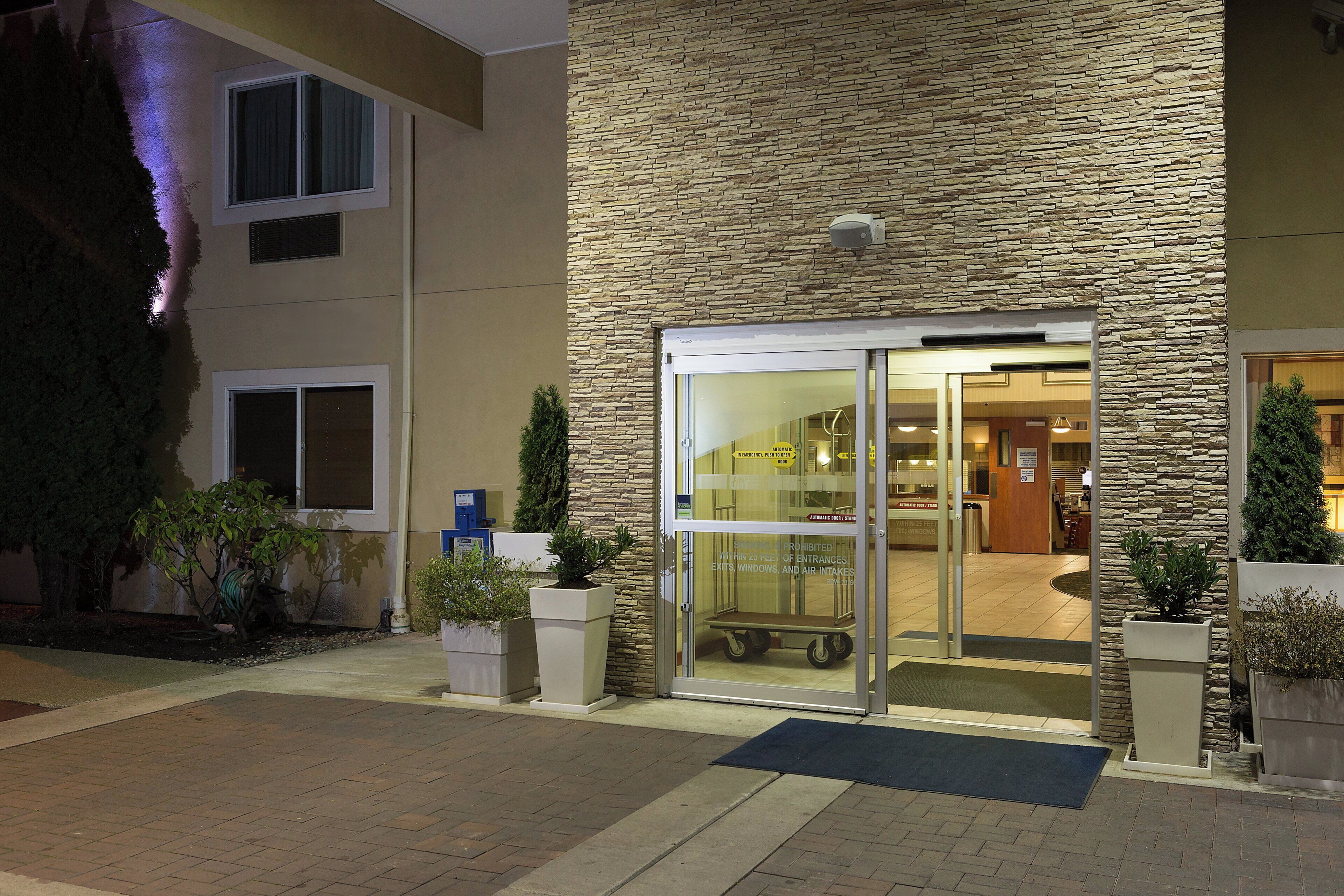A hotel entrance with a stone facade, glass doors, and a visible interior with a reception area.