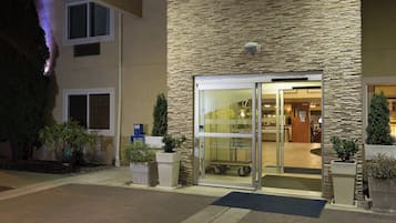 A hotel entrance with a stone facade, glass doors, and a visible interior with a reception area.