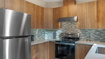 Een moderne keuken met houten kasten, een roestvrijstalen koelkast, een ingebouwde oven en een betegelde spatwand.