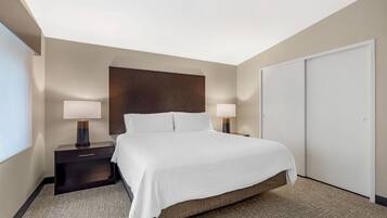 A hotel room with a large bed, two bedside tables with lamps, a wardrobe, and a carpeted floor.