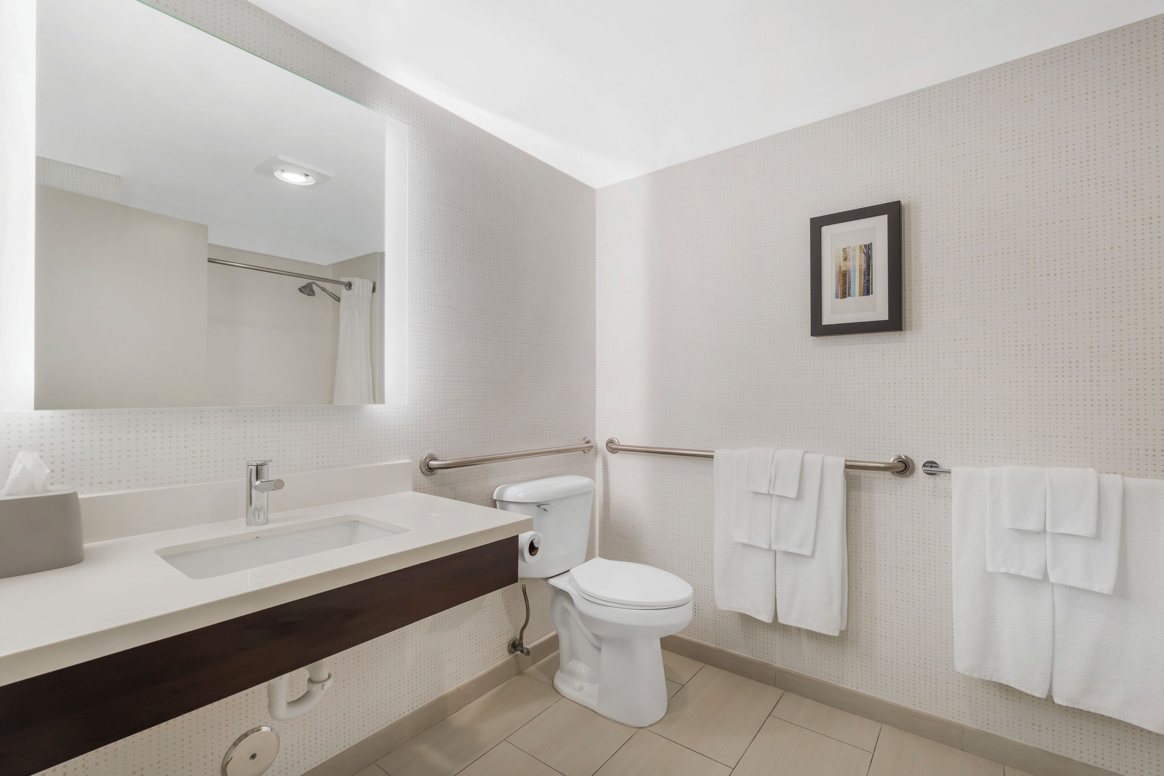 A modern bathroom with a large mirror, a sink, a toilet, and a towel rack.