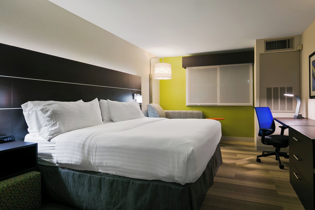 Una camera d'albergo con un letto, un comodino, una scrivania, una sedia e una televisione.