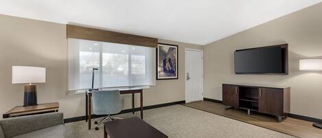A modern living room with a flat-screen TV, a coffee table, a sofa, a lamp, a painting, and a whiteboard.