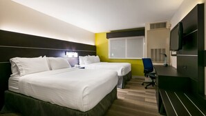 Ein Hotelzimmer mit zwei Betten, einem Schreibtisch, einem Stuhl, einem Fernseher und einem Fenster.