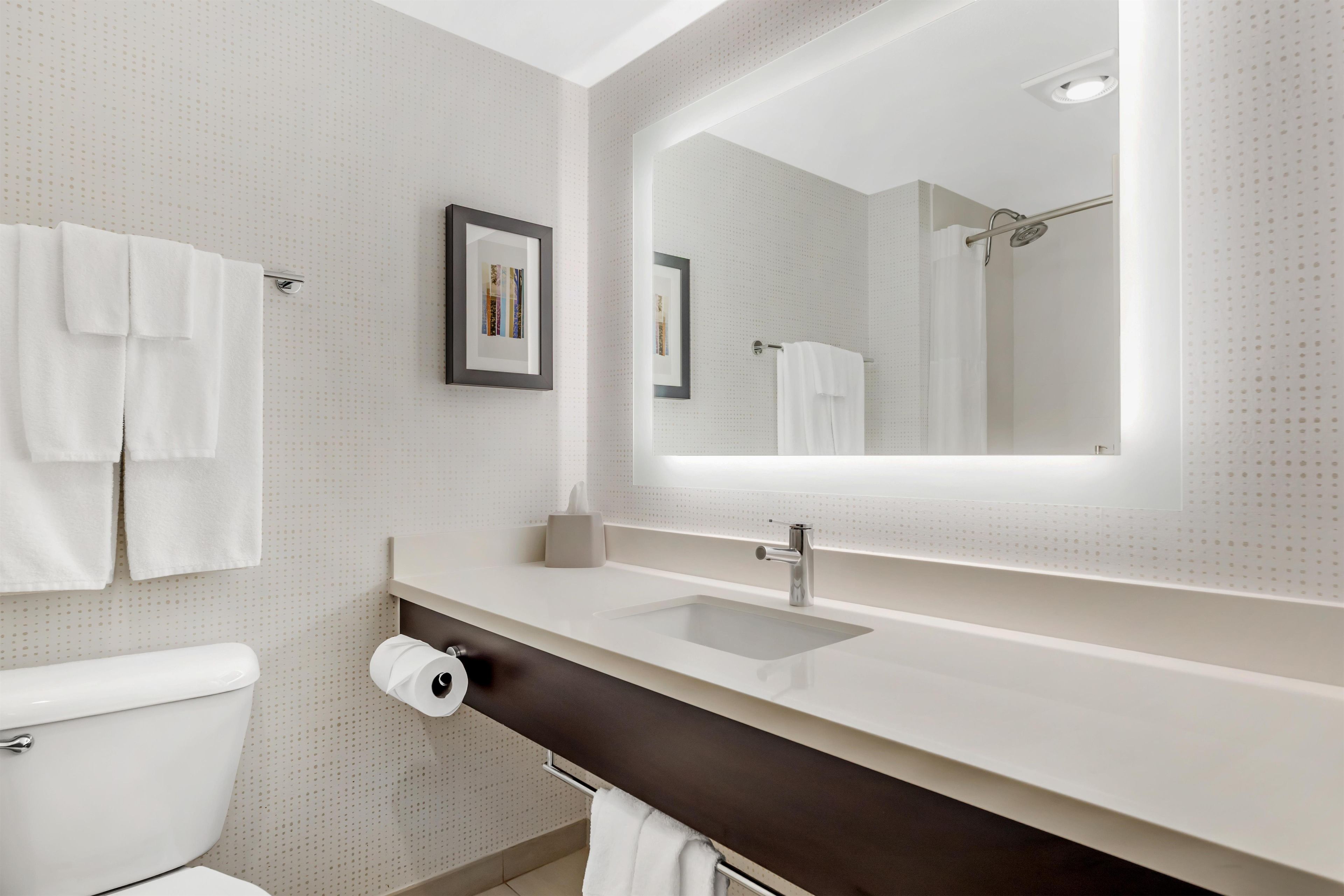 A modern bathroom with a toilet, sink, and large mirror.