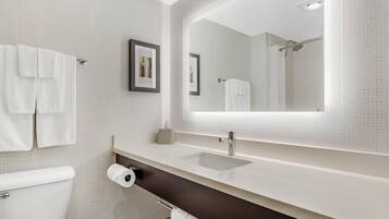 A modern bathroom with a toilet, sink, and large mirror.