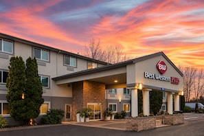Un hotel Best Western Plus con fachada de piedra, ventanas grandes y estacionamiento.