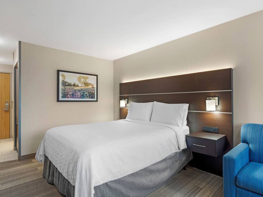 A hotel room with a bed, bedside table, and a chair.