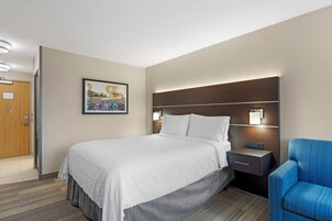 Quarto de hotel com cama, mesa de cabeceira e uma cadeira.