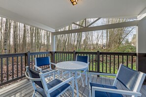 A covered outdoor seating area with a round table and four chairs, surrounded by a wooden deck and a railing. - Best Western Plus Burlington Skagit Valley Inn (Burlington)