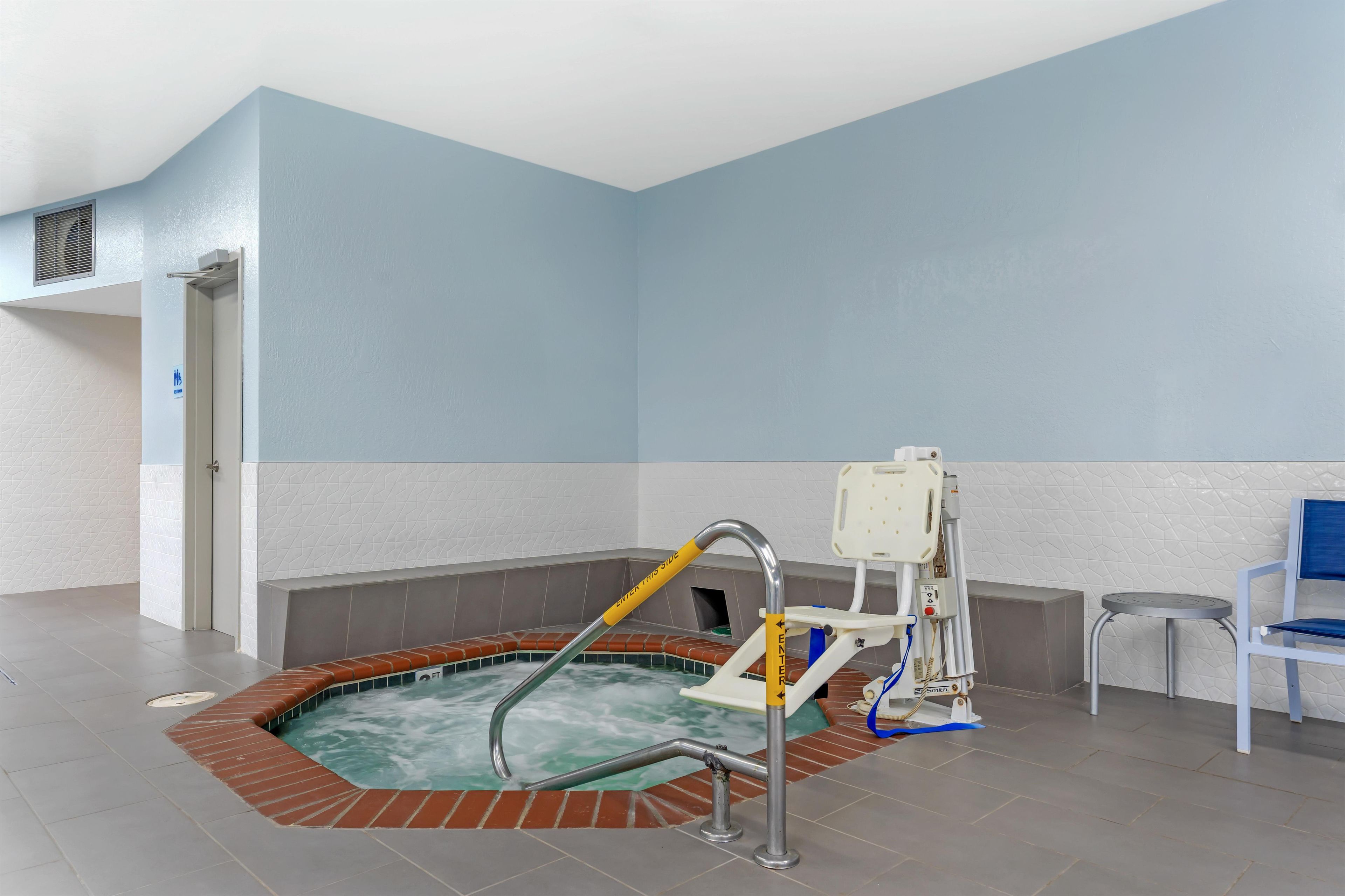 Un espacio de spa con un jacuzzi, una silla de masaje y una pequeña mesa.