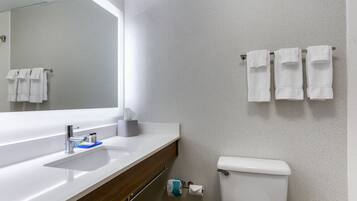 Un baño moderno con un espejo grande, un lavamanos y un inodoro.