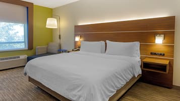 A hotel room with a large bed, a bedside table, a lamp, and a window.