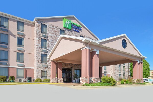 A Holiday Inn Express hotel with a brick facade, a covered entrance, and a clear blue sky.