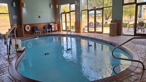 Ein hallenbad mit klarem Wasser, einem Rettungsschwimmerstuhl und einer Poolleiter.