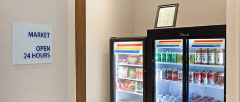 A vending machine with a sign indicating the market is open 24 hours.