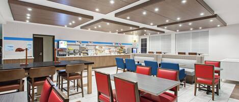A modern restaurant with booths and tables, a counter with food items, and a clean, well-lit interior.