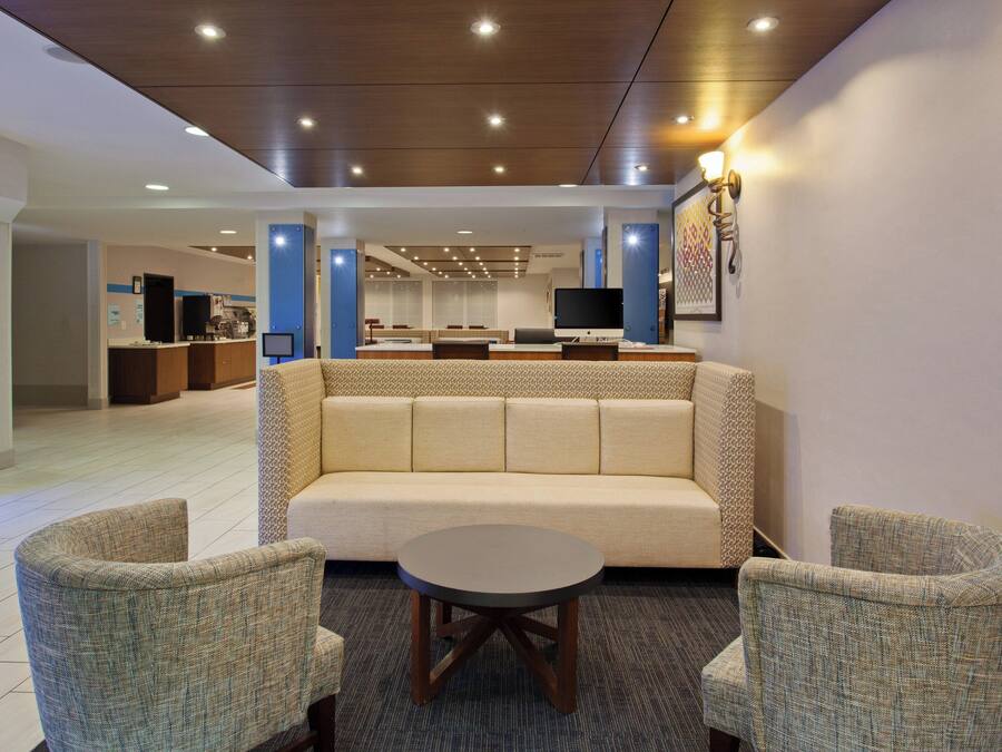 A lobby with a sofa, two armchairs, a coffee table, a TV, and a reception desk.