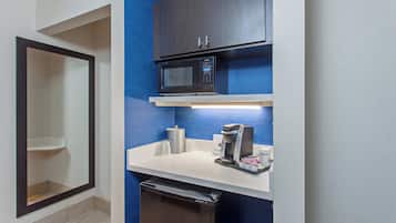 A compact kitchenette with a microwave, coffee maker, and a small refrigerator.