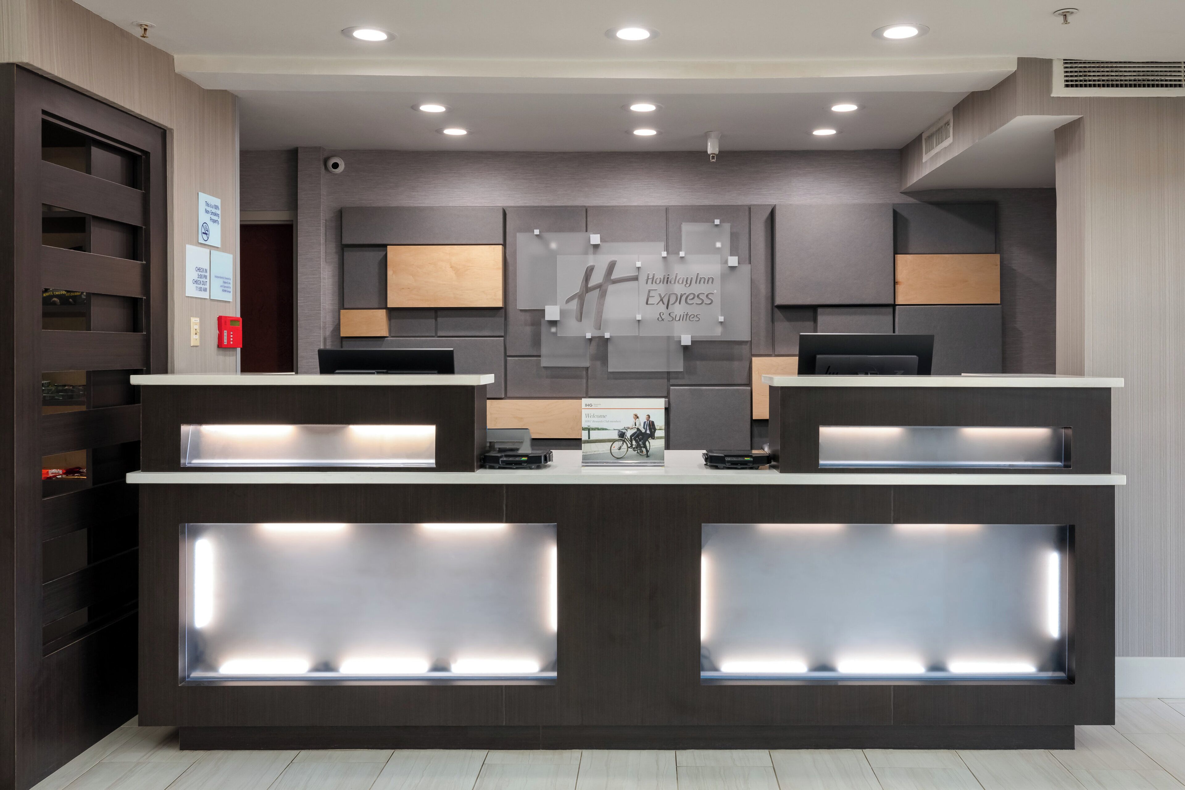 Een receptiebalie met een digitaal incheckpunt, een wandbordje met Holiday Inn Express & Suites en een receptiegedeelte met een houten paneeldecor.