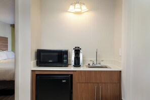Eine kompakte Küchenzeile mit Mikrowelle, Kaffeemaschine und Geschirrspüler.