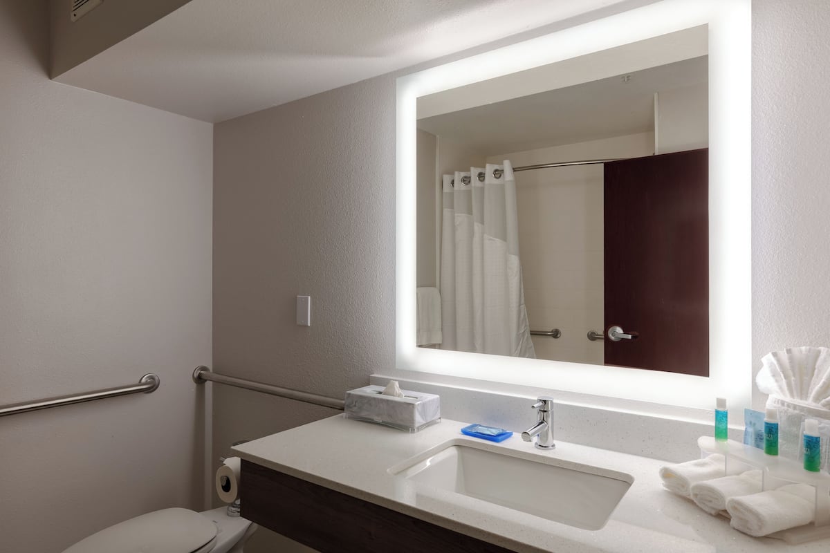A modern bathroom with a white sink, a mirror, a towel rack, and a toilet.