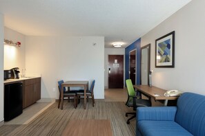 Ein kompaktes Hotelzimmer mit Küchenzeile, einer Essecke und einer Sitzecke mit Sofa und Sesseln.