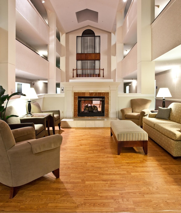 A spacious living room with a fireplace, high ceilings, and a balcony.