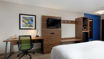 Una habitación de hotel con una cama, un escritorio con una silla, un televisor y una estantería.