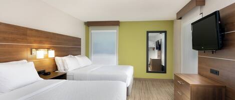 A hotel room with two beds, a TV, a mirror, and a wooden dresser.