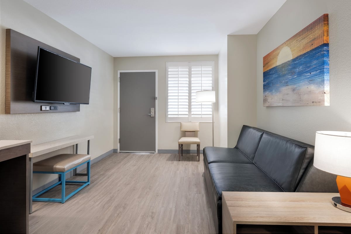 A modern living room with a flat-screen TV, a sofa, a bench, a table, and a painting on the wall.