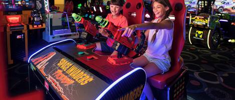 A space-themed arcade game with a neon sign, other arcade machines, and a patterned floor.