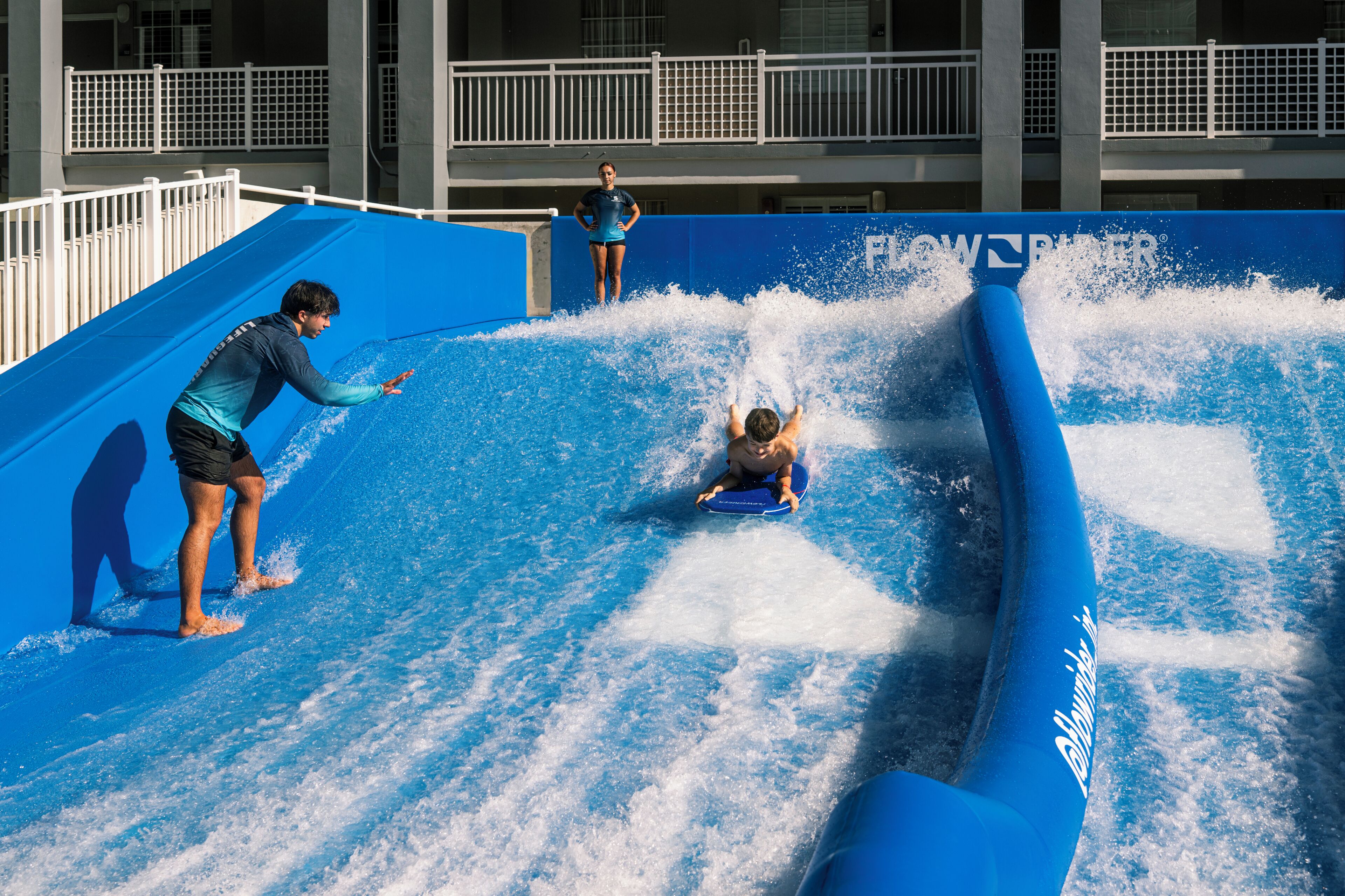 Une toboggan aquatique avec une personne qui dévale la pente et une autre personne qui se tient en haut.