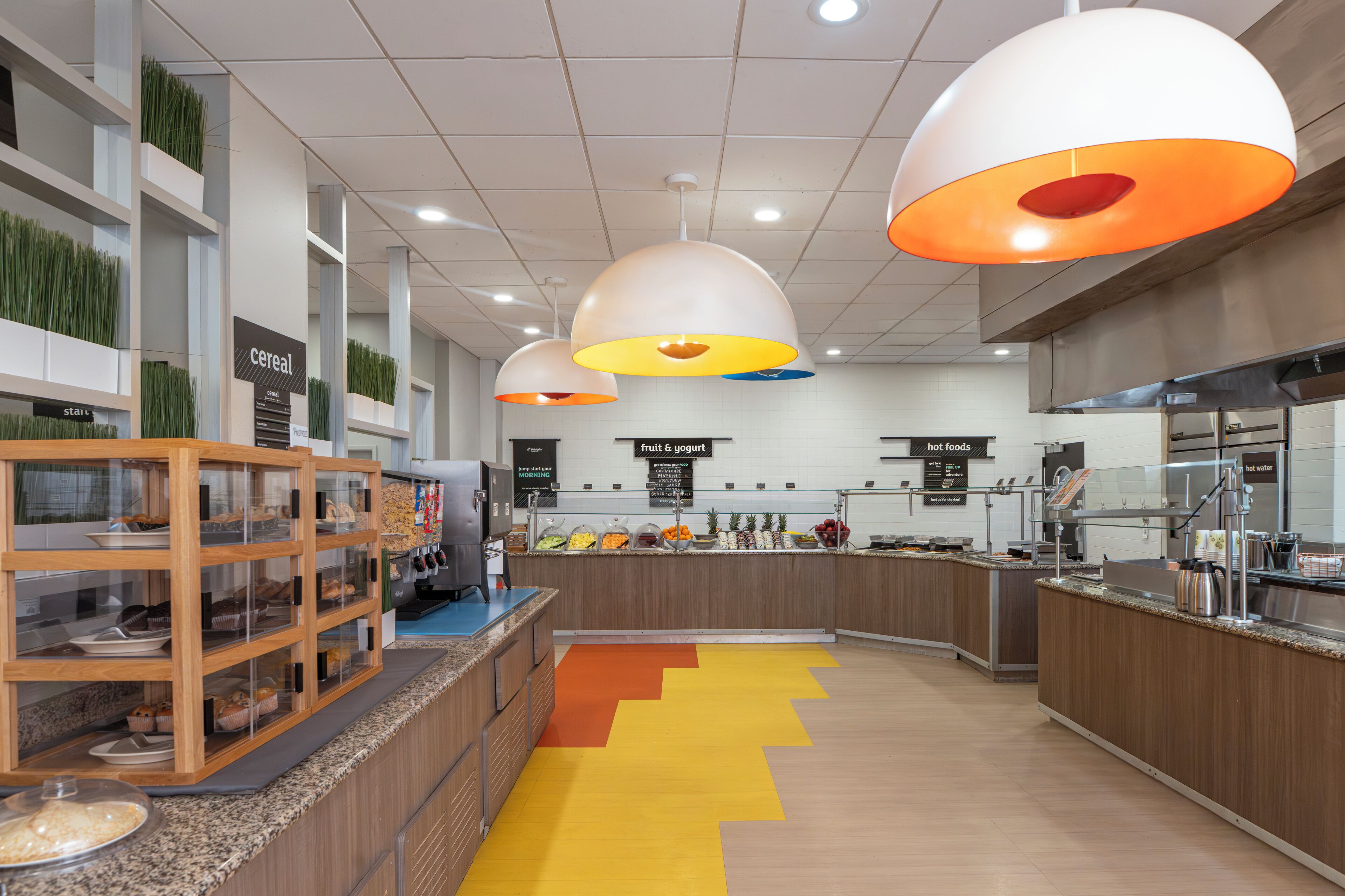 Une cuisine moderne dotée d’un îlot central, d’un espace dédié aux fruits et aux yaourts, et d’un présentoir pour les céréales.