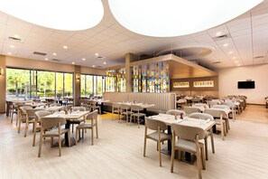 Un restaurant spacieux, doté de hauts plafonds, de grandes fenêtres et d’un décor intérieur moderne.