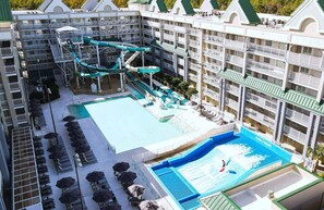 A hotel with a pool area, including a water slide and lounge chairs.