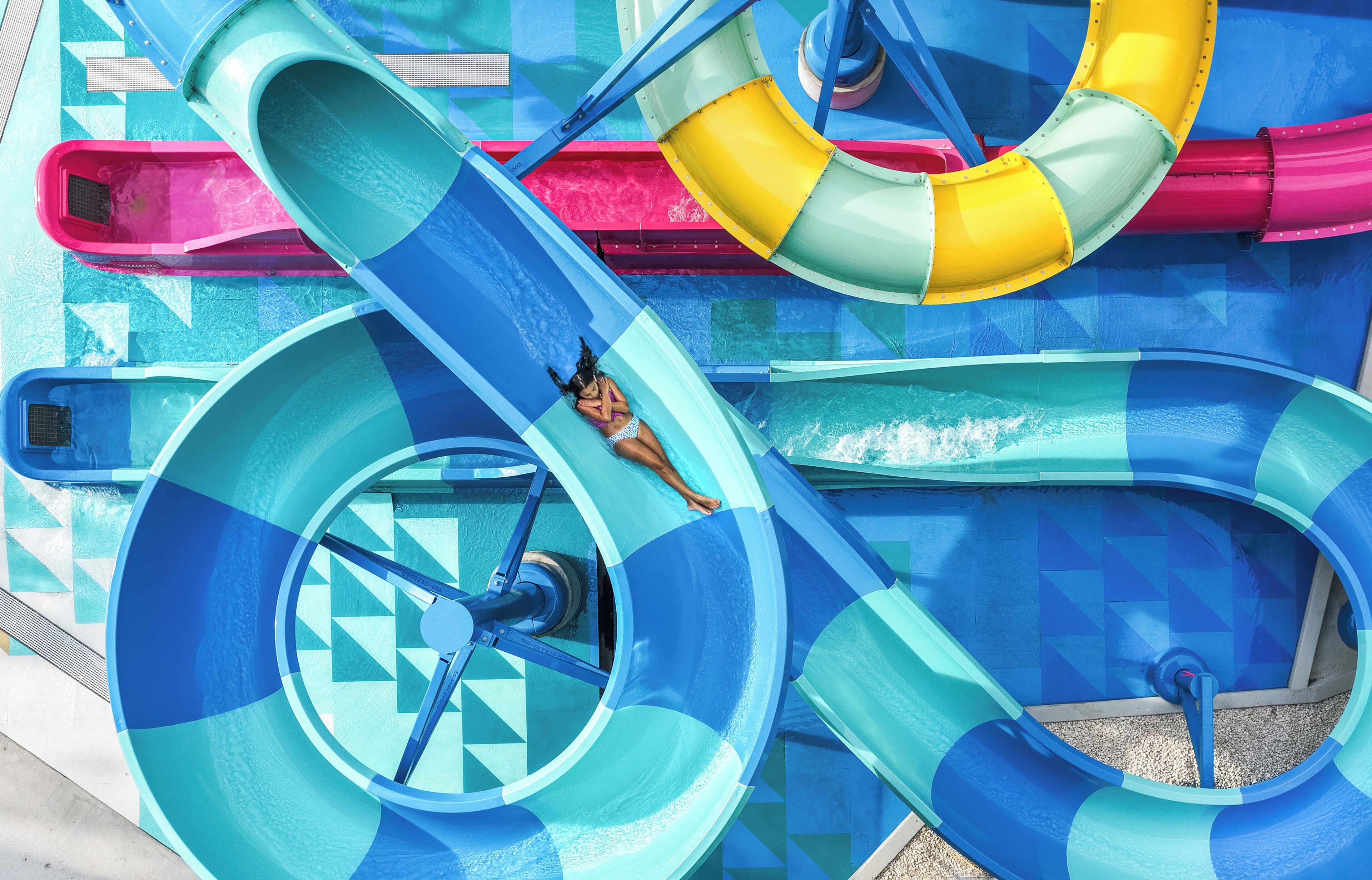 A water slide with a person at the bottom, surrounded by blue and yellow water slides.
