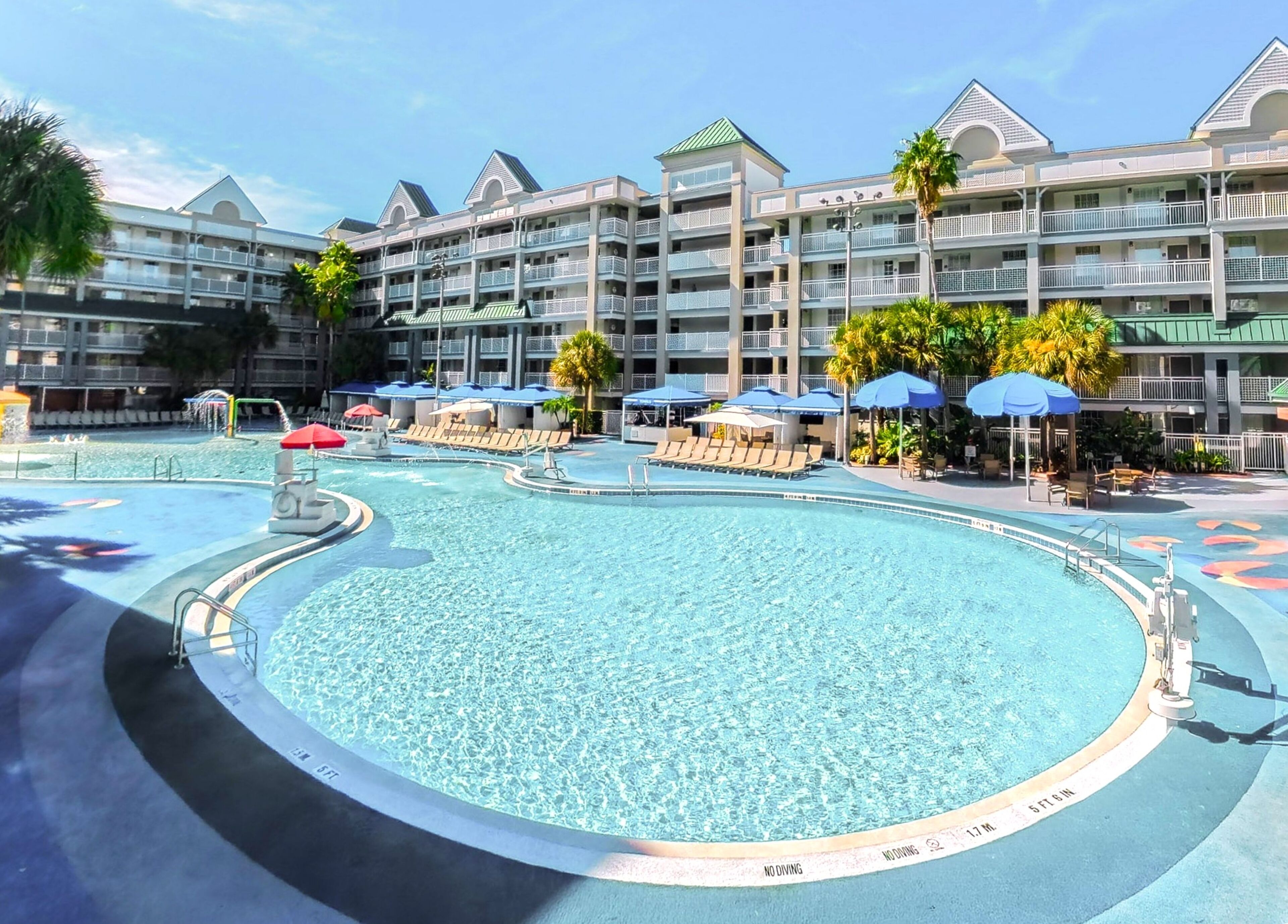 Un hôtel doté d’une grande piscine, de nombreux balcons et de parasols.