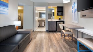 A modern hotel room with a sofa, a dining area, a kitchen, and a TV. - Holiday Inn Resort Orlando Suites - Waterpark by IHG (Orlando)